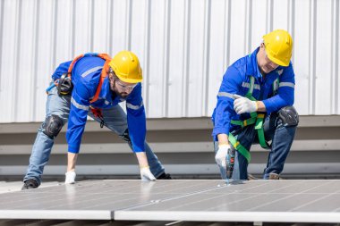 Mühendisler, bir sanayi fabrikasının çatısına güneş panelleri kurup denetlemeyi ayarlıyorlar. Ekip teknisyeni güneş pilini kontrol edip tamir ediyor. Alternatif yenilikçi güç çevresi.