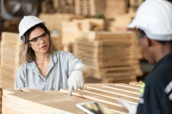 安全制服と硬い帽子の作業品質を身に着けている女性 木を製造するワークショップで木製品の検査 女性大工労働者木材倉庫産業 ストック写真