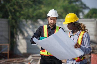 İnşaat mühendisi ve kadın Afro-Amerikan inşaat alanındaki iş kalitesini kontrol ediyor. Altyapı inşaatında çalışan çeşitli uluslardan oluşan bir ekip..
