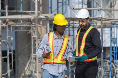 İnşaat mühendisi ve kadın Afro-Amerikan inşaat alanındaki iş kalitesini kontrol ediyor. Altyapı inşaatında çalışan çeşitli uluslardan oluşan bir ekip..
