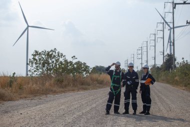 Ekip mühendisi rüzgar türbini işçi üniforması güvenlik anketi operasyon planlama yel değirmeni temiz enerjisini tartışıyor. Alternatif teknoloji çevreyi korur küresel ısınma sorunlarını azaltır.