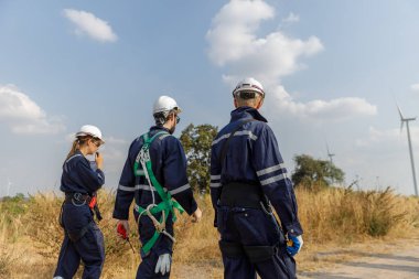 Ekip mühendisi rüzgar türbini işçi üniforması güvenlik anketi operasyon planlama yel değirmeni temiz enerjisini tartışıyor. Alternatif teknoloji çevreyi korur küresel ısınma sorunlarını azaltır.