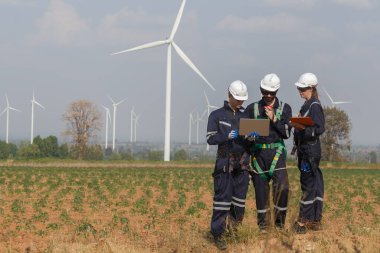 Dizüstü bilgisayarı tutan güvenlik üniforması giyen mühendis istasyon enerji rüzgârında yenilenebilir enerjiyle ilgili planı tartıştı. teknoloji çevreyi korur küresel ısınma sorunlarını azaltır.