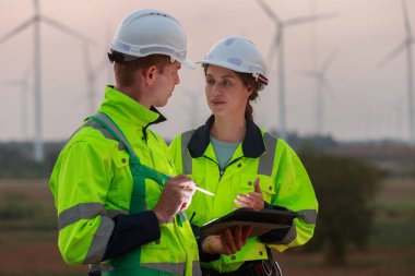Engineer wearing safety uniform using tablet discussed plan about renewable energy at station energy power wind turbine. technology protect environment reduce global warming problems. clipart