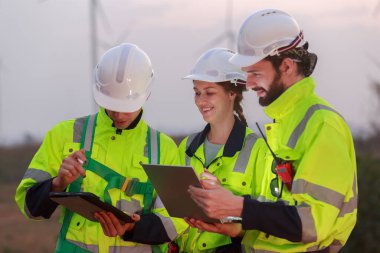 Güvenlik üniforması giyen mühendis, istasyon enerji rüzgar türbinindeki yenilenebilir enerji planlarını tartıştı. teknoloji çevreyi korur küresel ısınma sorunlarını azaltır.