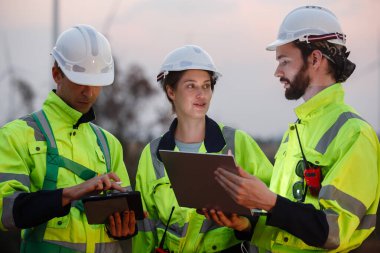 Güvenlik üniforması giyen mühendis, istasyon enerji rüzgar türbinindeki yenilenebilir enerji planlarını tartıştı. teknoloji çevreyi korur küresel ısınma sorunlarını azaltır.