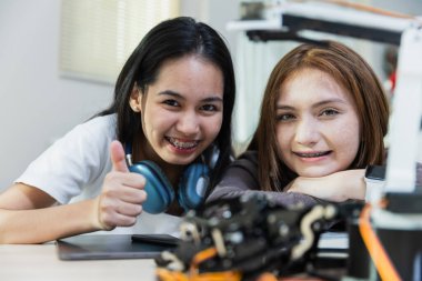 Sınıfta diş teli takan iki genç kızın el robotu eğitimi almasına sevindim. Gelecekteki yapay zeka için robot elektroniği öğreniyorum. Sistem becerisi eğitimi. STEM eğitimi