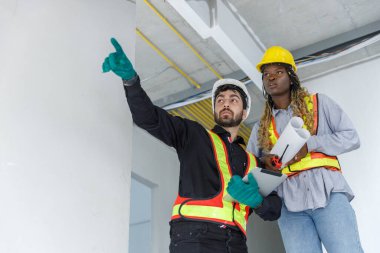 İnşaat mühendisi ve kadın Afro-Amerikan inşaat alanında tablet kontrol kalitesi kullanıyor. Altyapı inşaatında çalışan çeşitli uluslardan oluşan bir ekip..
