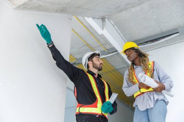 İnşaat mühendisi ve kadın Afro-Amerikan inşaat alanında tablet kontrol kalitesi kullanıyor. Altyapı inşaatında çalışan çeşitli uluslardan oluşan bir ekip..