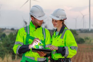 Tablet kullanarak güvenlik üniforması giyen ekip mühendisi istasyon enerji rüzgârında yenilenebilir enerji hakkında tartıştı. teknoloji çevreyi korur küresel ısınma sorunlarını azaltır.