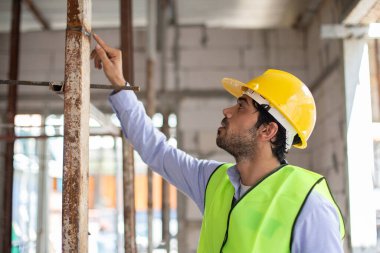İnşaat mühendisi adam bina yapısının kalitesini kontrol ediyor. Erkek mimar inşaattaki yapı üzerinde kalite denetimi yapıyor. Ustabaşı iş yerinde.