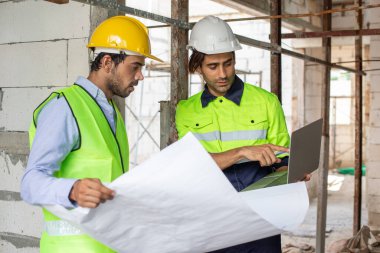 Adam mühendis, bina inşaatında şablon çizimi tutuyor. Erkek mimar ev inşaatında duruyor. Ustabaşı iş yerinde.