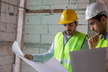 Adam mühendis, bina inşaatında şablon çizimi tutuyor. Erkek mimar ev inşaatında duruyor. Ustabaşı iş yerinde.