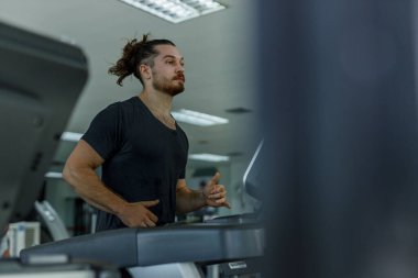Spor giyimli genç beyaz adam spor salonunda koşu bandı koşuyor. Sporcu kas zayıflığı motivasyonu fitness kalorileri yakar sağlık için kilo kaybeder.