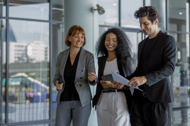 Çeşitli iş adamları modern ofiste buluşmaya gidiyor. İş adamları ve iş kadını tablet ve belge kağıtlarıyla sohbet ediyorlar. Müdürün emri ofise giderken işe yarar..