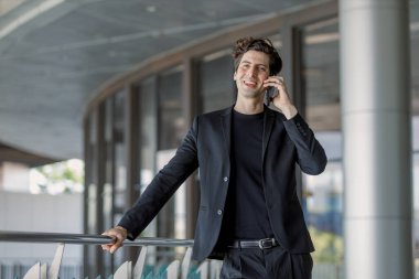 Kendine güvenen, çekici iş adamı konuşan cep telefonlu genç adam dışarıda çalışmak ve konuşmak için acele ediyor. Ceo akıllı konuşma cep telefonu başarılı ortak.