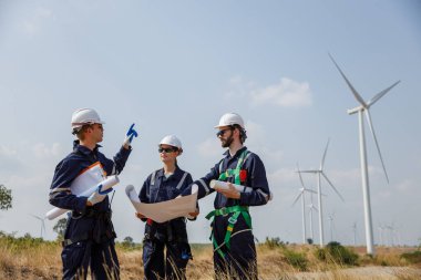 Ekip mühendisi rüzgar türbini işçi üniforması güvenlik anketi operasyon planlama yel değirmeni temiz enerjisini tartışıyor. Alternatif teknoloji çevreyi korur küresel ısınma sorunlarını azaltır.