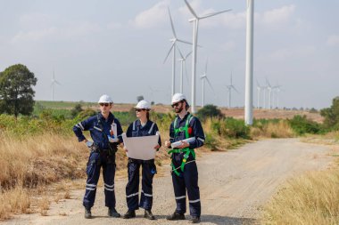 Ekip mühendisi rüzgar türbini işçi üniforması güvenlik anketi operasyon planlama yel değirmeni temiz enerjisini tartışıyor. Alternatif teknoloji çevreyi korur küresel ısınma sorunlarını azaltır.