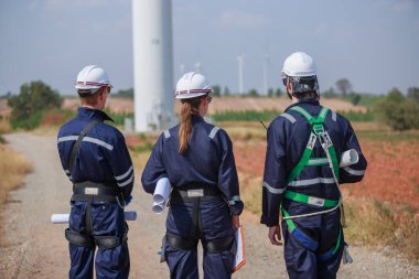 Ekip mühendisi rüzgar türbini işçi üniforması güvenlik anketi operasyon planlama yel değirmeni temiz enerjisini tartışıyor. Alternatif teknoloji çevreyi korur küresel ısınma sorunlarını azaltır.
