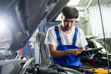 Ulaşım onarım servisi konsepti, Tamirci oto tamircisi içerideki hasarı kontrol etmek için tablet kullanıyor. Erkek işçi servis motoru tamirhanesi.