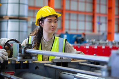 Kadın mühendis, fabrikada çalışırken şapka takıyor. Kadın teknisyen metal torna endüstrisini kontrol ediyor. Kadın atölye teknolojisi üretimi.