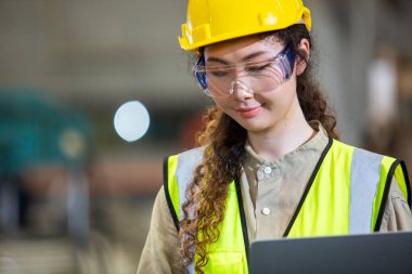 Kadın mühendis imalat fabrikasında çalışırken dizüstü bilgisayar kullanıyor. Kadın işçi teknisyen metal işçiliği otomatik mekanik enerji projesi.