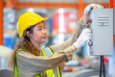 Kadın mühendis panel kontrol makinesinin güç düğmesini çeviriyor. İş düğmesine basıyorum. Mühendislik endüstriyel santrallerdeki makineleri çalıştırmaya çalışıyor..