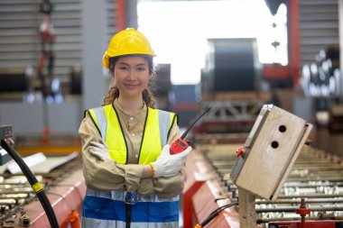 Kadın mühendis elinde telsiz kalite kontrolüyle fabrika işleten metal deposunun makinesinde duruyor. profesyonel mühendislik makine atölyesi.