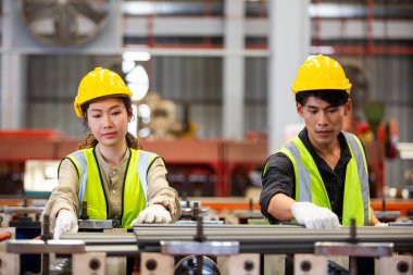 Erkek ve kadın işçiler fabrikadaki demir üretimini kontrol etmek için kırmızı kask takıyorlar. Ağır sanayi işyerindeki ustabaşı..