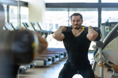 Kaslı adam kum torbasıyla egzersiz yapıyor ve ağırlık kaldırıyor. Kol ve omuz kaslarını güçlendir. Ağırlık kaldırma egzersizi..