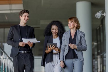 Çeşitli iş adamları modern ofiste buluşmaya gidiyor. İş adamları ve iş kadını tablet ve belge kağıtlarıyla sohbet ediyorlar. Müdürün emri ofise giderken işe yarar..