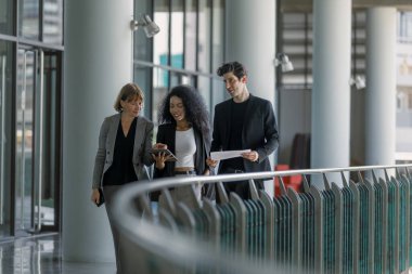Çeşitli iş adamları modern ofiste buluşmaya gidiyor. İş adamları ve iş kadını tablet ve belge kağıtlarıyla sohbet ediyorlar. Müdürün emri ofise giderken işe yarar..
