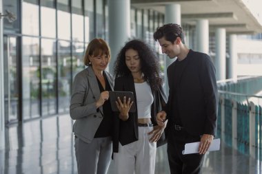 Çeşitli iş adamları modern ofiste buluşmaya gidiyor. İş adamları ve iş kadını tablet ve belge kağıtlarıyla sohbet ediyorlar. Müdürün emri ofise giderken işe yarar..