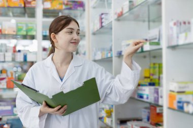 Çalışan kadın eczacılar eczanedeki raflarda bulunan seçkin ilaçlardır. Eczanedeki ürünlerin bilgi çeşitliliği için uyuşturucu satıcısı ilaç kontrolü.