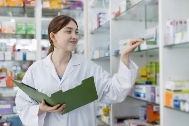 Çalışan kadın eczacılar eczanedeki raflarda bulunan seçkin ilaçlardır. Eczanedeki ürünlerin bilgi çeşitliliği için uyuşturucu satıcısı ilaç kontrolü.