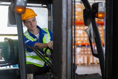 Adam fabrikada güvenlik kaskı sürücüsü forklift deposu takıyor. Endüstriyel erkek işçi. Konteynır kutusunu kontrol et. Lojistik ihracat konsepti.