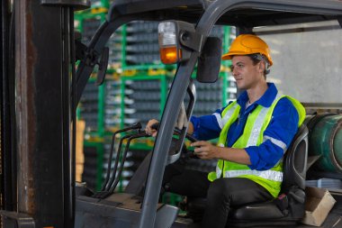 Adam fabrikada güvenlik kaskı sürücüsü forklift deposu takıyor. Endüstriyel erkek işçi. Konteynır kutusunu kontrol et. Lojistik ihracat konsepti.