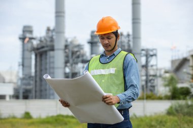 Asyalı işçi santral fabrikasının portresi. Taslak başparmak havada ve gülümsüyor. Güvenlik üniforması kaskı takan bir mühendis. Adam elektrik jeneratörü onarım operasyonları. elektrikçi enerji endüstrisi