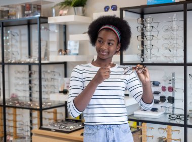 Portre mutlu genç kadın Afro-Amerikan saç tebessümü optik dükkanında duran gözlük takıyor. modern göz doktoru konsepti.