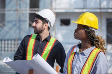 İnşaat mühendisi ve kadın Afro-Amerikan inşaat alanındaki iş kalitesini kontrol ediyor. Altyapı inşaatında çalışan çeşitli uluslardan oluşan bir ekip..