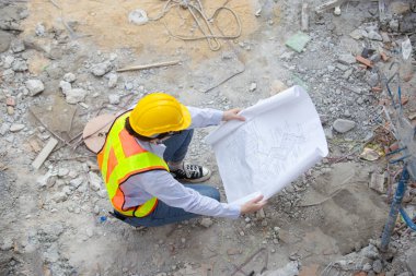 Şantiyede çalışan planlı bir kadın işçi. Kadın mühendis inşaat sahasında sarı yelek giyiyor. Planlı sivil iş planlama yapıyor. Üst görünüm.