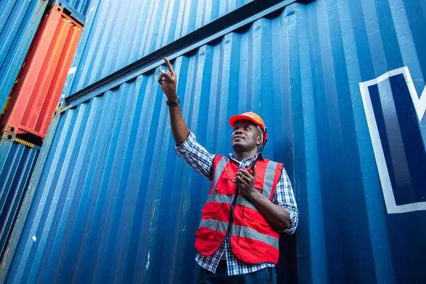 stock image Man american african with talkie walkie at worker industry dock or container yard. foreman talking radio working control loading cargo shipping transport.