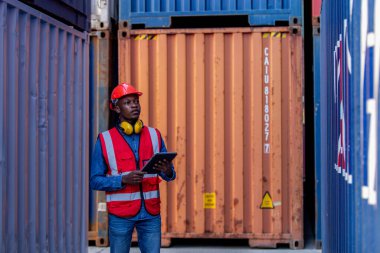 Üniformalı erkek Afro-Amerikan Mühendislik portresi kasketli, tablet takıyor ürün otantik konteynır deposunu kontrol ediyor. Alan lojistik ihracat ve nakliye.