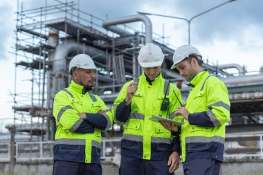 Profesyonel elektrik mühendisi üniforması. Petrol petrokimyasını rafine etmek için birlikte çalışıyorlar. Tablet kullanıyorlar. Endüstriyel fabrika alan kontrol enerji santrali.