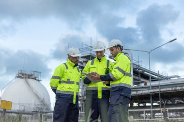 Profesyonel elektrik mühendisi üniforması. Petrol petrokimyasını rafine etmek için birlikte çalışıyorlar. Tablet kullanıyorlar. Endüstriyel fabrika alan kontrol enerji santrali.