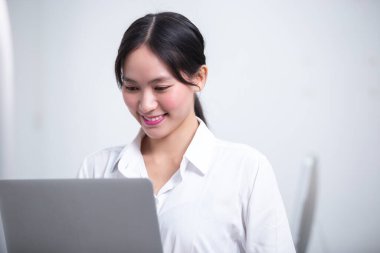 Genç bayan güzel Asyalı, pazarlama ofisinde dizüstü bilgisayar kullanarak çalışıyor. Mutlu iş kadını yönetici pozitif öğrenme projesinde çalışmaktan memnun.. 