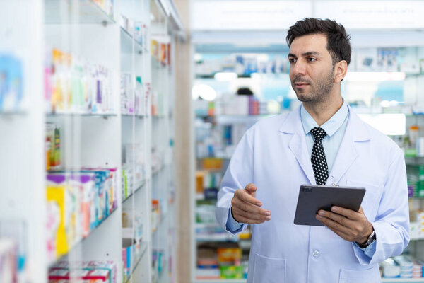 man pharmacists are selecting medications for patients online via tablet in drug store. Drug seller use tablet check for information before sending to patient.