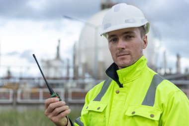 Profesyonel mühendis güvenlik üniforması ve petrol petrokimya fabrikası rafine eden tankın yakınındaki çalışma alanı giyiyor. Sanayi fabrikası enerji santrali.