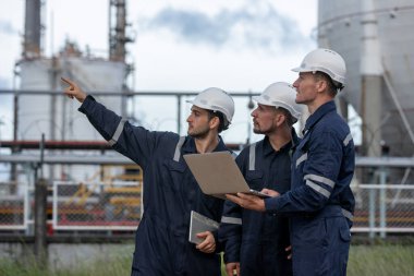 Ekip mühendisi, petrol petrokimya fabrikasını rafine etmek için tank istasyonunda dizüstü bilgisayar kullanıyor. Teknisyen petrol sanayi fabrikasının çevresindeki tank kalitesini gösteriyor..
