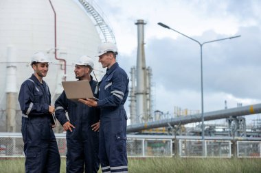 Ekip mühendisi, petrol petrokimya fabrikasını rafine etmek için tank istasyonunda dizüstü bilgisayar kullanıyor. Teknisyen petrol sanayii fabrikasında danışmanlık kalitesinden bahsediyor.